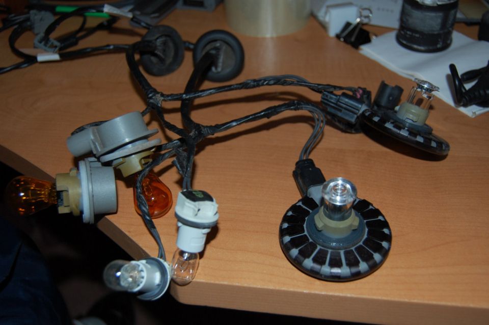Automotive taillight wiring harness with sockets and amber/clear bulbs on a table