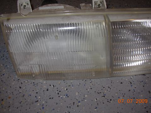 1995 Ford Taurus - Close-up of a vehicle headlight assembly, showing the textured lens and mounting hardware. The date 07.07.2009 is visible in the corner.
