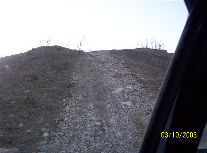 Steep rocky off-road hill climb trail seen from inside a vehicle, timestamped 03/10/2003