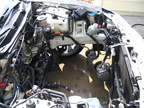 1994 Acura Integra - Engine bay of a car undergoing repair, showing disassembled components and the open space where the engine was.