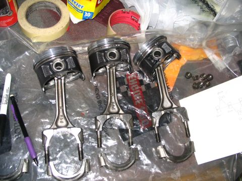 1994 Acura Integra - Engine parts, including pistons and connecting rods, are arranged on a surface with various tools and a diagram.