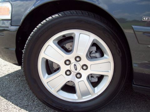 2004 Ford Crown Victoria - The front passenger side wheel and fender of a dark-colored 2004 Ford Crown Victoria are shown.