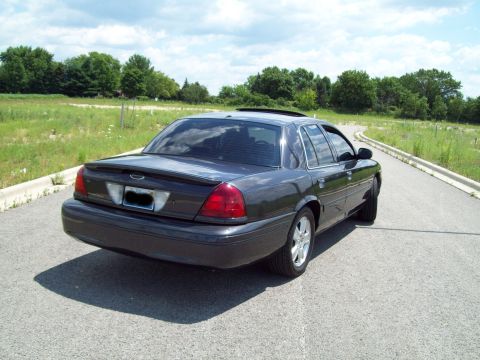 2004 Ford Crown Victoria - Rear view of a dark 2004 Ford Crown Victoria parked on a paved road.