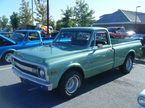 1991 Nissan Micra - Green 1970 Chevrolet C10 pickup truck parked next to a blue pickup truck.