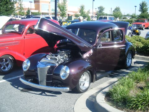 1991 Nissan Micra - A custom hot rod coupe is parked next to a red classic car, both with their hoods open.