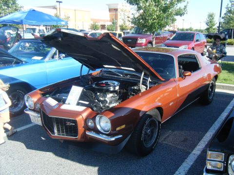 1991 Nissan Micra - This orange coupe, likely from the 1970s, is displayed with its hood open, revealing the engine and a Z28 badge on the grille.