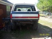 1987 Ford Bronco - This 1980s Ford Bronco is seen from the rear, a distinctive red, white, and blue stripe across its tailgate.