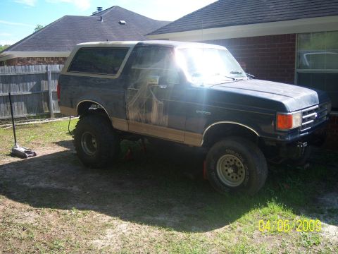 1987 Ford Bronco - This lifted 1987 Ford Bronco is parked in a grassy yard with a house in the background.