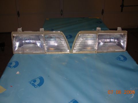 1995 Ford Taurus - This image shows a pair of clear headlights, likely for a vehicle, resting on a blue tarp.