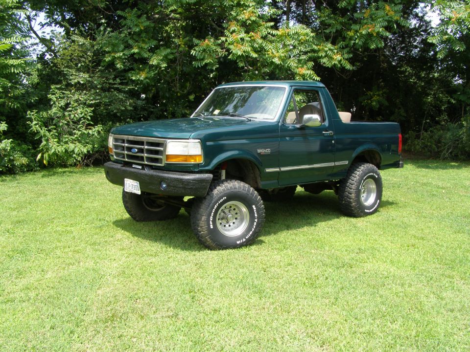 Green 1993 Ford Bronco with lifted suspension and off-road tires parked on grass