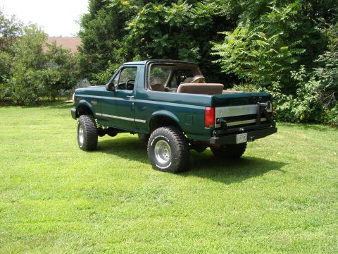 1993 Ford Bronco - This green Ford Bronco has its top removed and is parked on a grassy lawn.