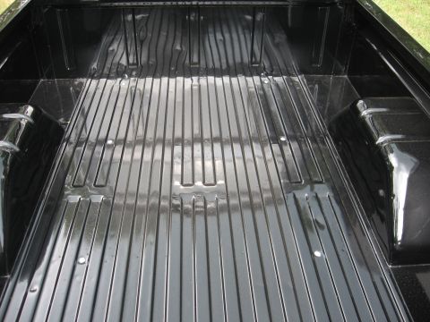 1966 Ford F-100 - The interior of a black truck bed with ribbed flooring.