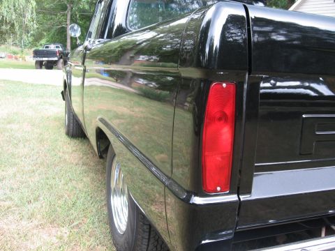 1966 Ford F-100 - Black Ford F-series truck with a second truck visible in the background.