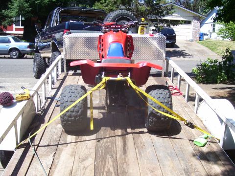 1991 Ford Bronco - ATV and pickup truck on a trailer, with a car in the background.