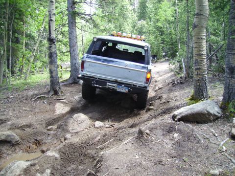 1978 Ford Bronco - This 1978 Ford Bronco navigates a challenging, rocky, and muddy off-road trail through a wooded area.