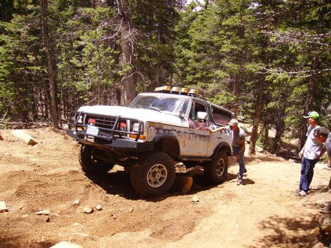 1978 Ford Bronco - A lifted 1978 Ford Bronco navigates a challenging off-road trail with onlookers.