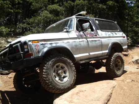 1978 Ford Bronco - A 1978 Ford Bronco navigates a rocky trail, its off-road modifications evident.