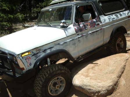 1978 Ford Bronco - This 1978 Ford Bronco navigates rocky terrain, its off-road modifications and weathered appearance.