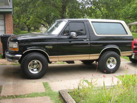 1994 Ford Bronco - Black Ford Bronco with tan trim and aftermarket wheels parked on a driveway.