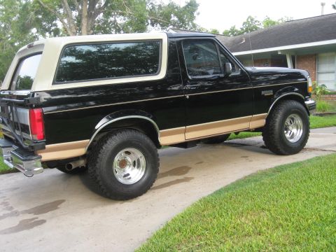 1994 Ford Bronco - This two-tone Ford Bronco is parked on a concrete driveway in front of a house.