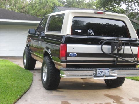 1994 Ford Bronco - This black and tan Ford Bronco features a spare tire carrier and aftermarket wheels.