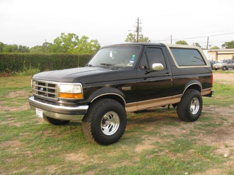 1994 Ford Bronco - This 1994 Ford Bronco features a two-tone black and tan paint scheme with prominent "Bronco" badging on the side.