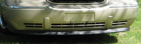 2000 Mercury Grand Marquis - Close-up of the front grille and bumper of a gold sedan parked on grass.