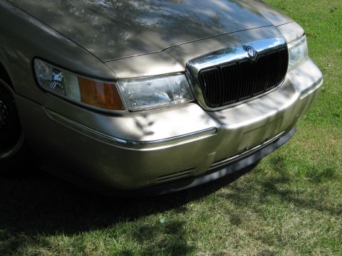 2000 Mercury Grand Marquis - Front view of a gold 2000 Mercury Grand Marquis, its distinctive chrome grille and headlights.
