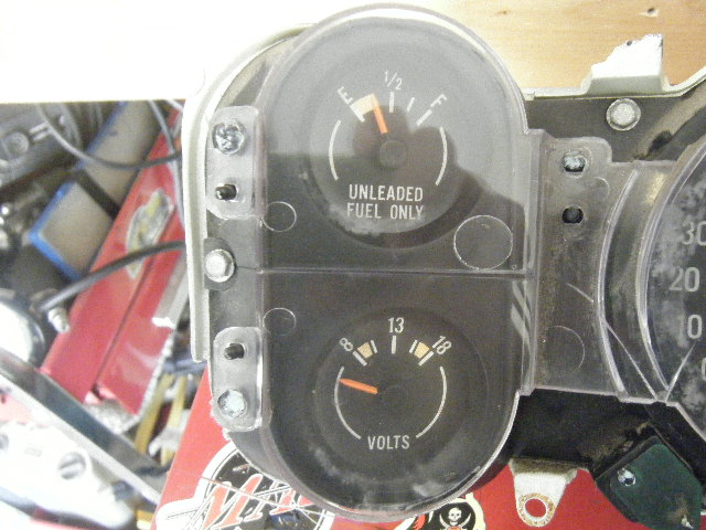 Vehicle dashboard with fuel and volts gauges. Text reads 'UNLEADED FUEL ONLY' and 'VOLTS'