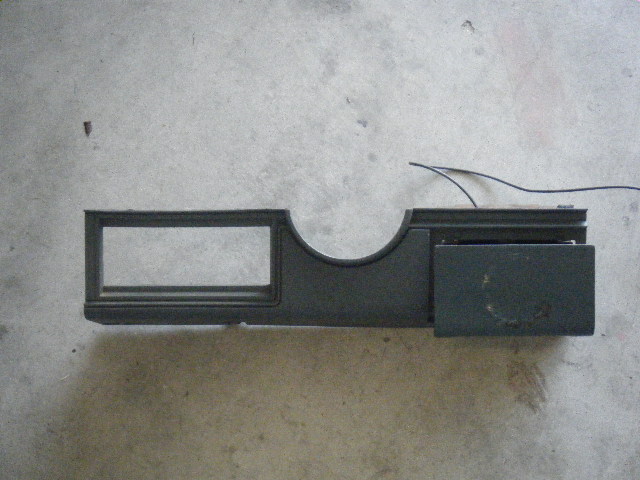 Dashboard trim piece with rectangular cutout and a small flip-down compartment