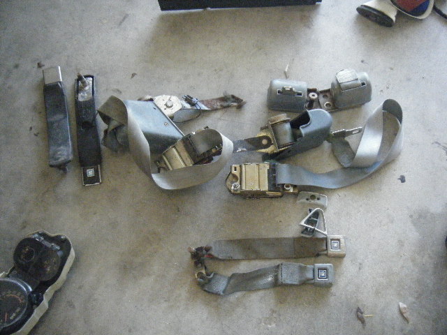 Car seat belts and a gauge cluster laid out on a concrete floor