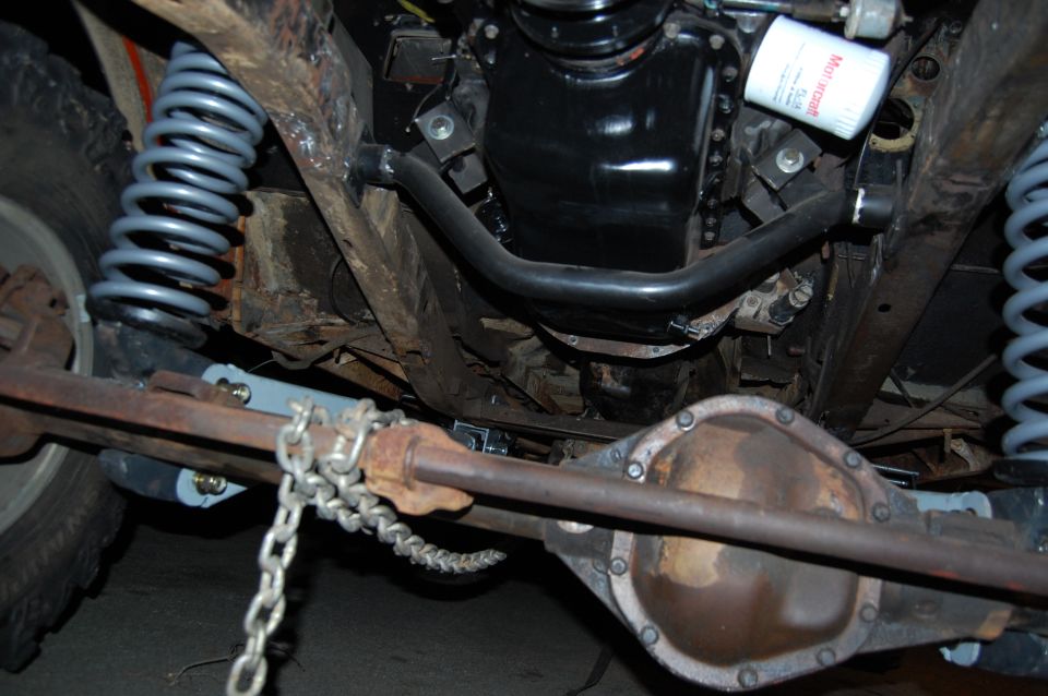 Underside view of a vehicle's suspension and drivetrain, showing the rear axle, springs, and part of the engine