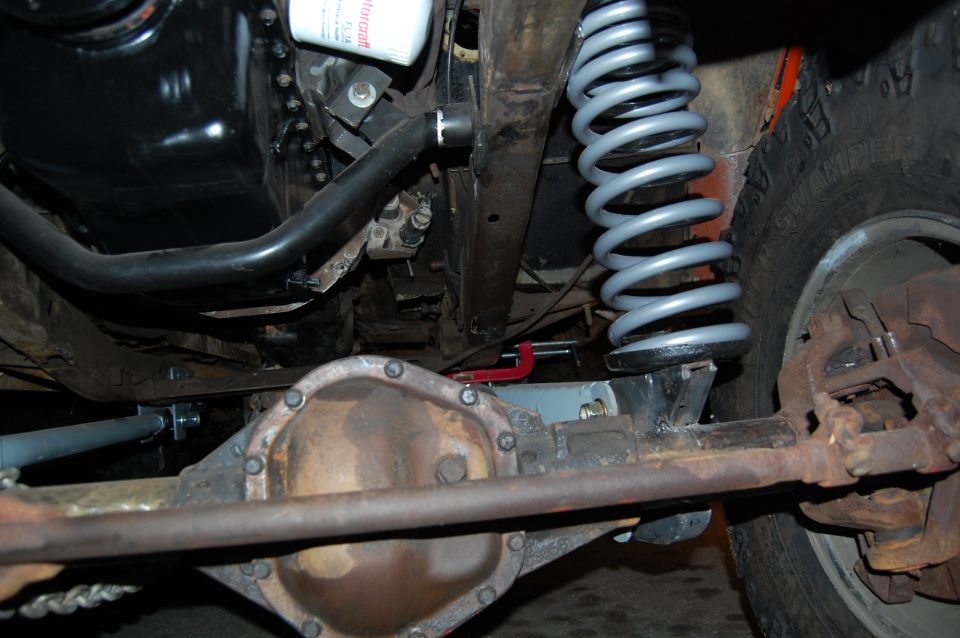 Undercarriage of a vehicle showing a differential, suspension spring, and oil filter