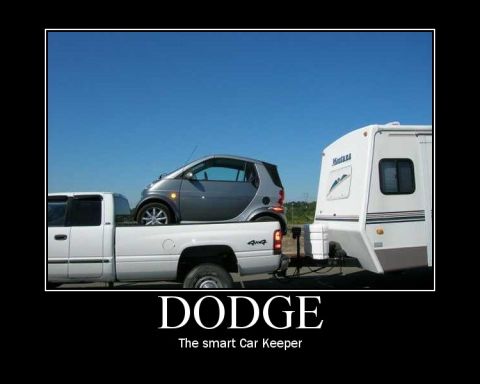 2008 Dodge 1500 - A pickup truck is loaded with a Smart car and also tows a travel trailer under a clear blue sky.