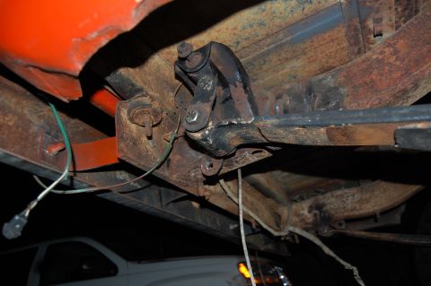 1994 Ford Bronco - The underside of a vehicle shows significant rust and exposed wiring, with another vehicle visible beneath.