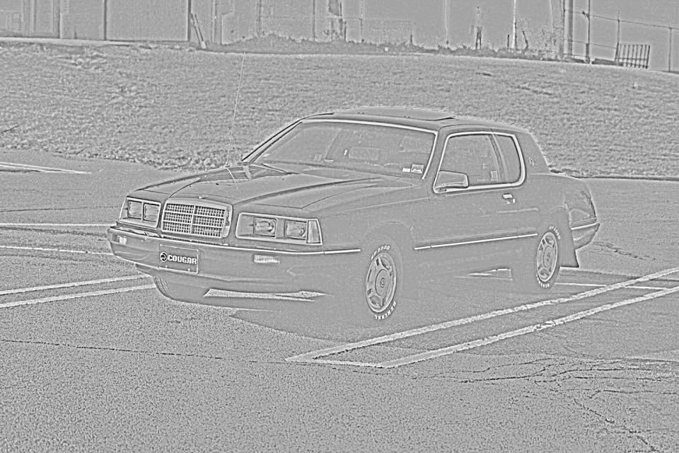 Dark-colored 1985 Mercury Cougar parked in a lot, front 3/4 view