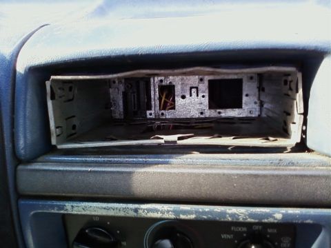1994 Ford F-250 - Interior view of a dashboard with the car stereo mount removed, showing exposed wiring and metal components.