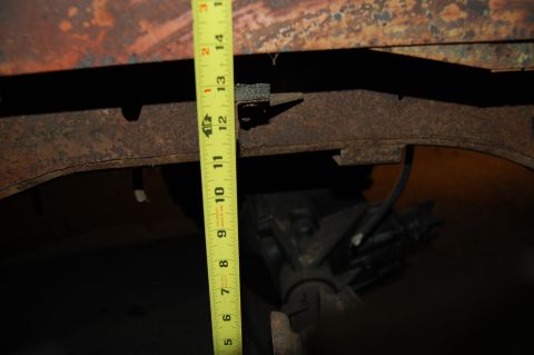 1994 Ford Bronco - A yellow tape measure is used to gauge the depth of a rusty frame section on an unidentified vehicle.