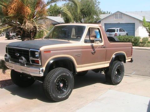 1985 Ford Bronco - A lifted 1980s Ford Bronco is parked in front of a suburban house.