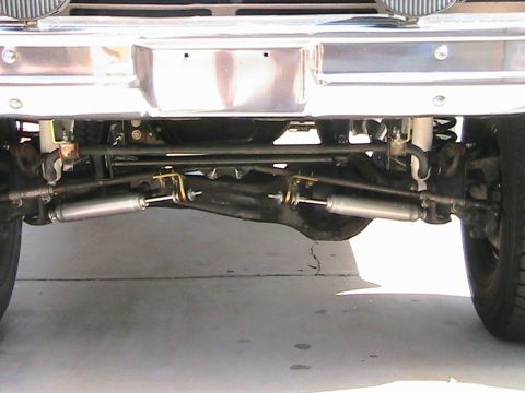 1985 Ford Bronco - Close-up of front steering linkage and stabilizer shocks.