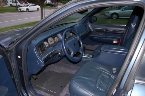1985 Mercury Grand Marquis - Interior view of a blue car, showing dashboard, steering wheel, seats, and floor mat.