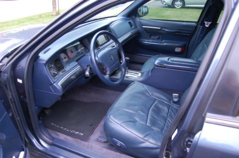 1985 Mercury Grand Marquis - The interior of the car features blue leather seats and a matching dashboard with a prominent steering wheel.