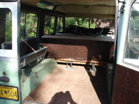 1967 Land Rover Land Rover - Interior of a 1967 Land Rover Land Rover, showing the seating and floor area. An Alaska license plate is visible on the exterior.