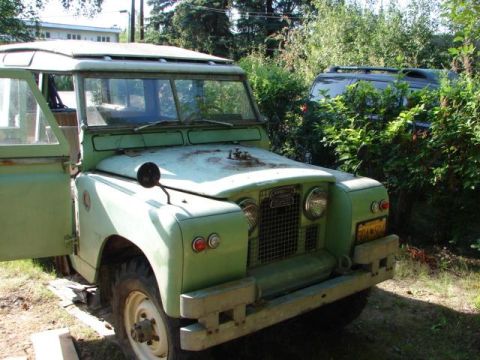 1967 Land Rover Land Rover - A light green 1967 Land Rover is parked outdoors with its driver's door open, partially obscured by foliage.