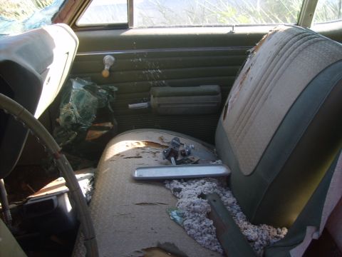 1971 Pontiac Lemans - The interior of a car shows significant wear and damage, including ripped upholstery and shattered glass.