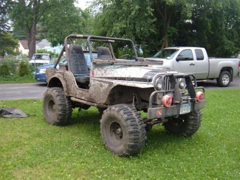 1976 Jeep CJ5 - This off-road vehicle is covered in mud, suggesting recent use on rough terrain.