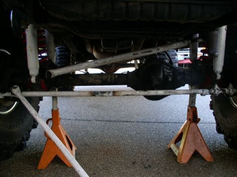 1979 Ford Bronco - The vehicle's undercarriage is supported by jack stands, revealing its suspension components and rear axle.