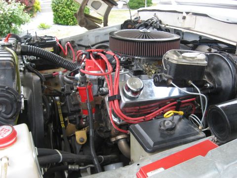1979 Ford Bronco - Close-up view of an engine bay chrome valve covers and prominent red spark plug wires.