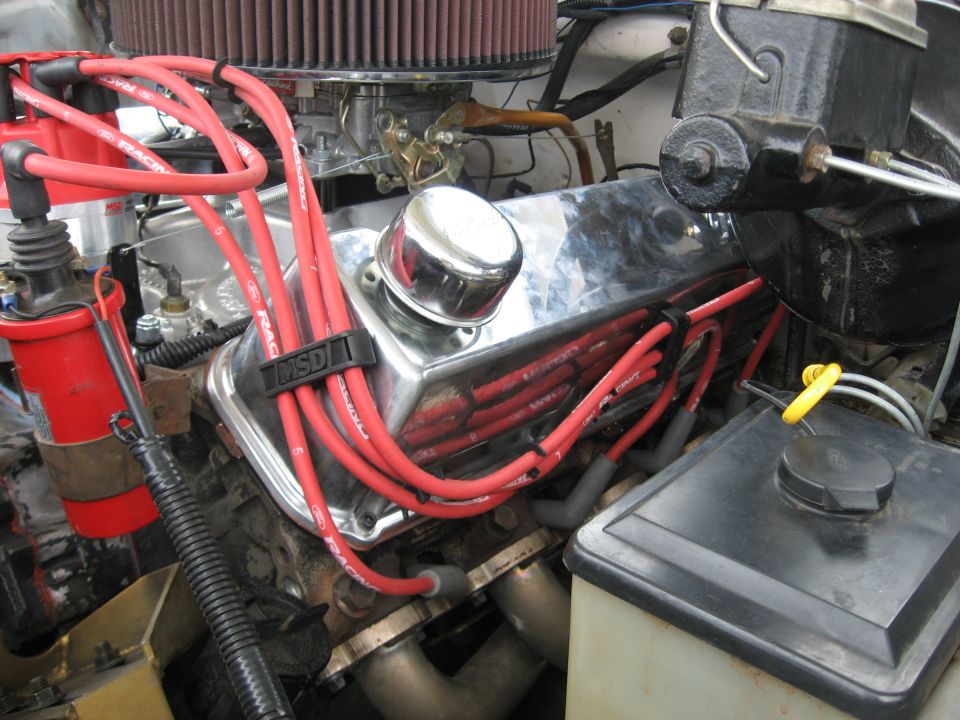 V8 engine with chrome valve cover, red spark plug wires, and chrome breather cap