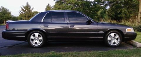 2004 Ford Crown Victoria - Side view of a dark gray 2004 Ford Crown Victoria Lx Sport sedan with tinted windows and a rear spoiler.
